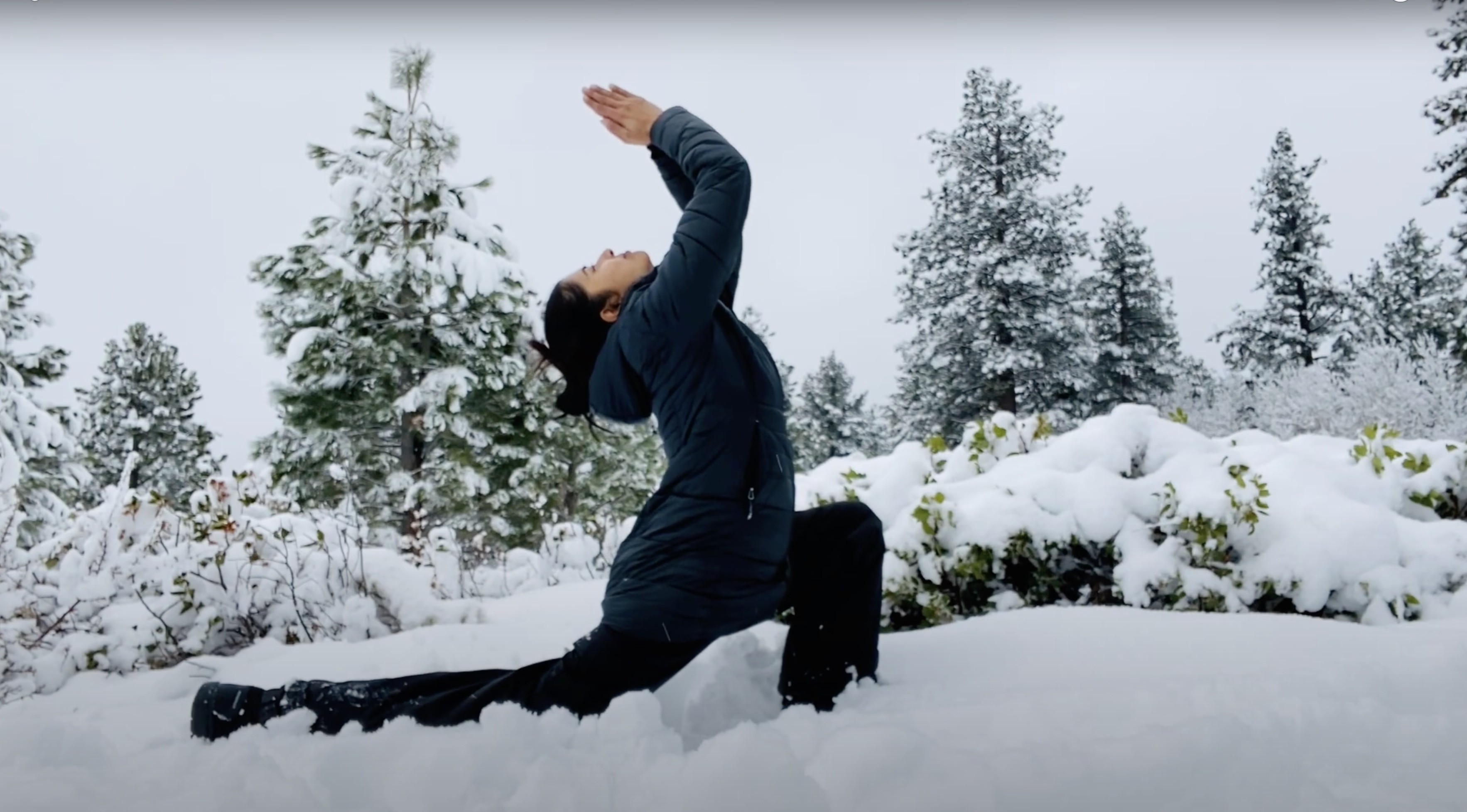 Yoga pose in fresh snow among pine trees