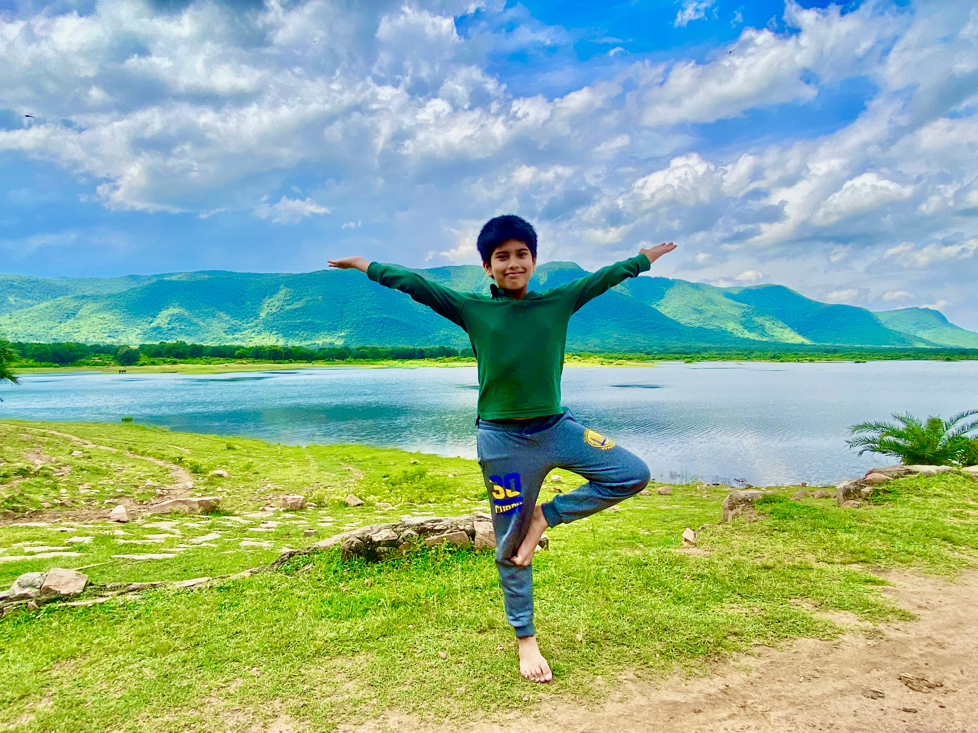 Young yogi in tree pose beside a mountain lake