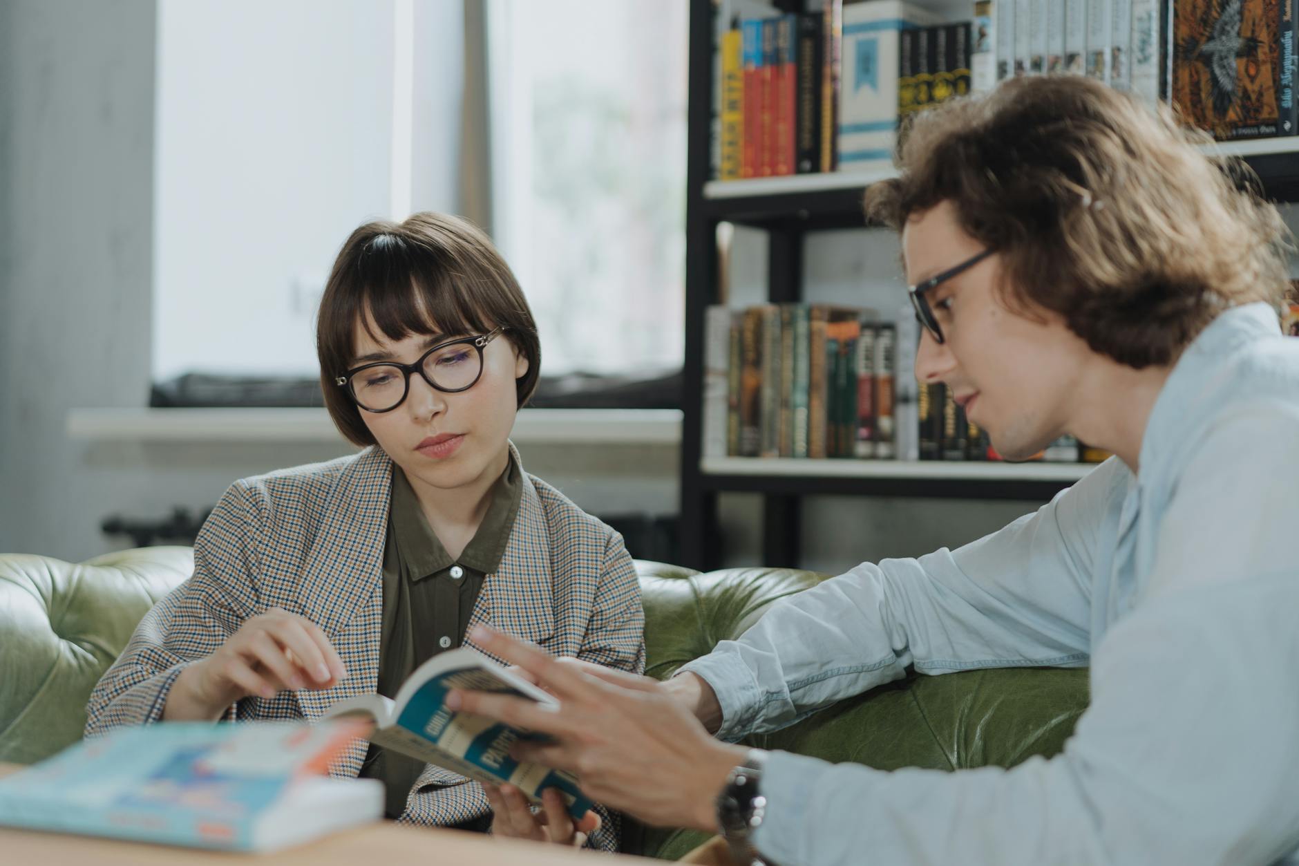 Boy in gray sweater wearing black framed eyeglasses reading